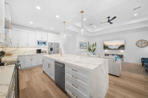 A modern kitchen with white cabinetry, a marble countertop, and stainless steel appliances. - LUXE: Home w/ 3 Kings, Pool & Spa, Bikes, BBQ (Naples)