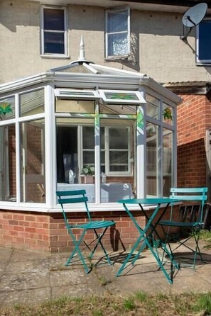 Enjoy the serene view from this conservatory with a brick exterior and tiled floor, featuring two comfortable chairs.