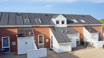 Une rangée de maisons mobiles blanches, avec des toits gris, une allée en gravier et un petit espace patio aménagé avec des meubles d’extérieur.