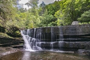 A waterfall cascading over a stone structure surrounded by lush greenery.