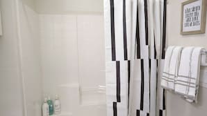 A bathroom with a shower curtain, a bathtub, and a towel rack with towels.