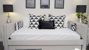 A bedroom with a bed, two lamps, and three framed pictures on the wall.