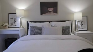 A neatly arranged hotel room with a large bed, two bedside tables, and a desk.