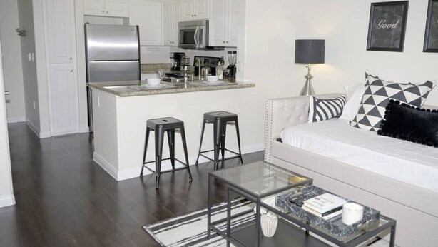 A modern kitchen with white cabinets, stainless steel appliances, and a central island with stools.