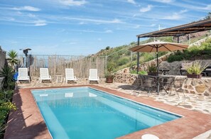 Relax by the serene pool surrounded by a patio, lounge chairs, and a shaded area.