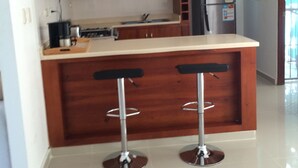 Una cocina con armarios de madera, un refrigerador de acero inoxidable y dos taburetes de bar.