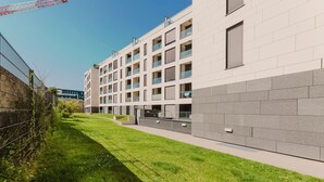 Un edificio moderno de varios pisos con techo plano, ventanas grandes y un sendero pavimentado.