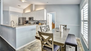A modern kitchen with white cabinets, a central island, and a dining area with a bench. - Tampa Paradise For All Occasions (Riverview)
