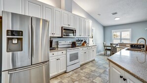 A modern kitchen with stainless steel appliances, white cabinetry, and a granite countertop. - Tampa Paradise For All Occasions (Riverview)