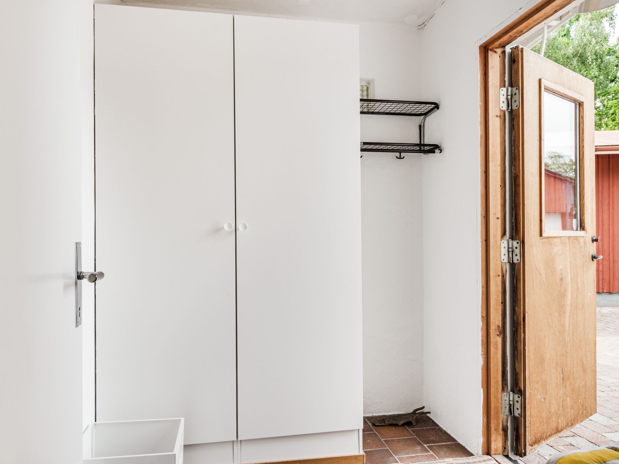 Ein weißer Schrank mit Tür, ein kleines weißes Regal und eine Holztür mit Fenster.
