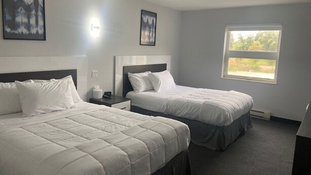 Ett hotellrum med två sängar, ett nattduksbord, ett fönster med utsikt och inramade konstverk på väggarna.