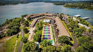 An aerial view of a hotel with a large swimming pool, surrounded by lush greenery and a lake. - Fun Awaits! Indoor & Outdoor Pool, Lake Access at Table Rock! (Kimberling City)