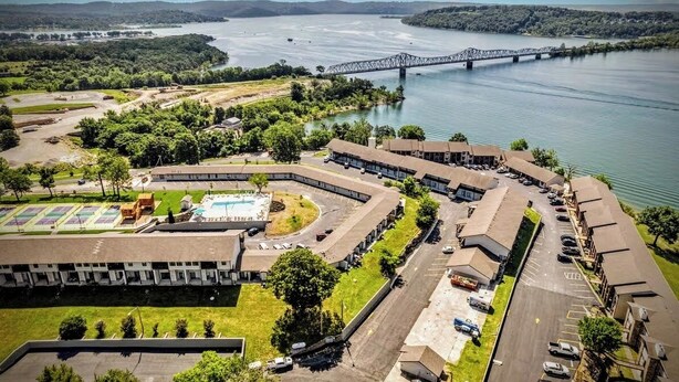 A large, multi-story hotel with a central courtyard, parking areas, and a view of a bridge over a river. - Fun Awaits! Indoor & Outdoor Pool, Lake Access at Table Rock! (Kimberling City)