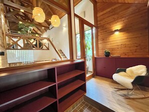Un interior moderno con una escalera de madera, una vitrina de cristal y una zona de estar acogedora.