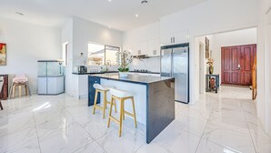 A modern kitchen with a large island, stainless steel appliances, and a marble floor. - StayAU 6BR Deluxe Lakeview Point Cook (Point Cook)