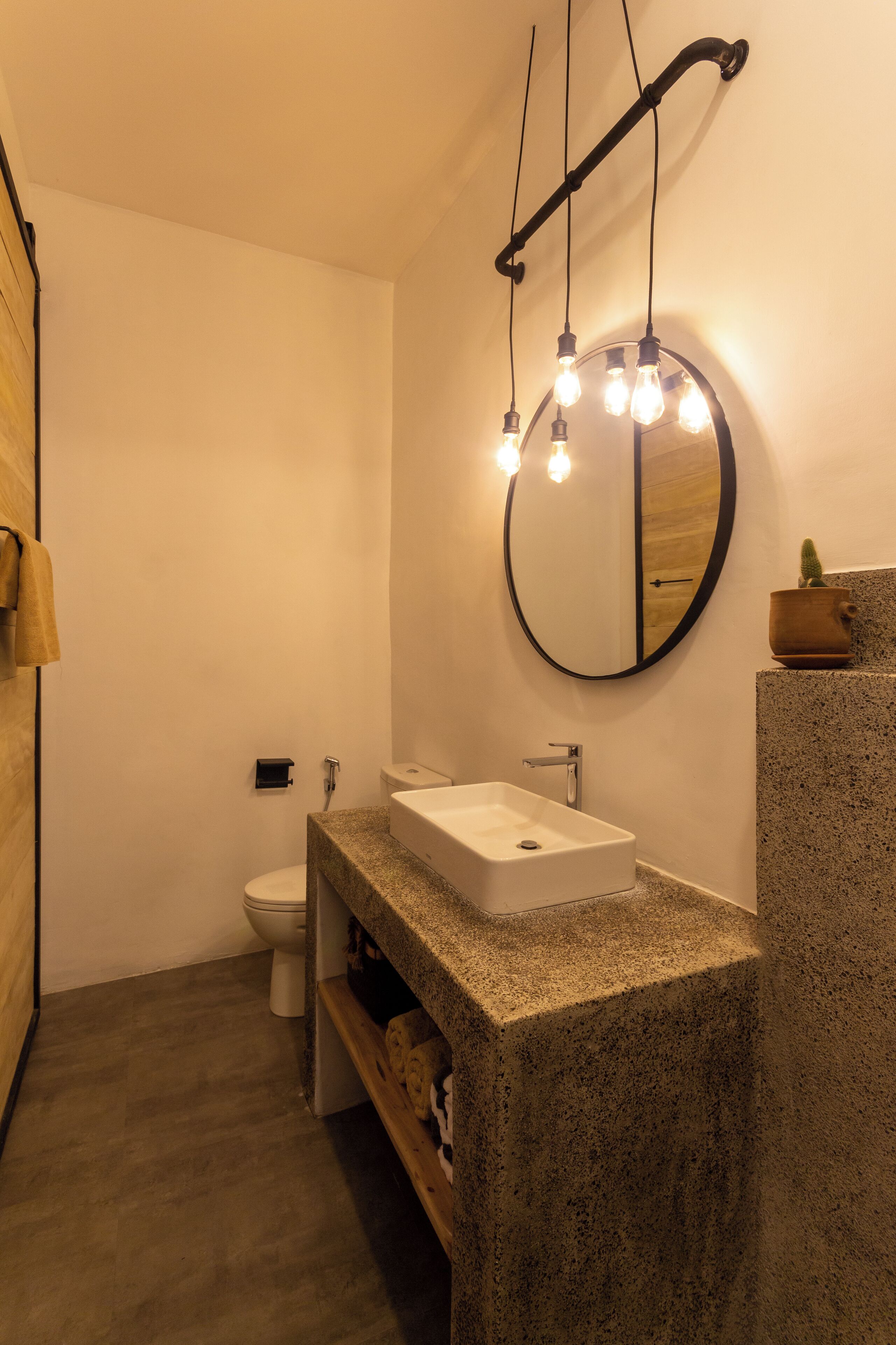 A modern bathroom with a granite countertop, a round mirror, and a toilet.