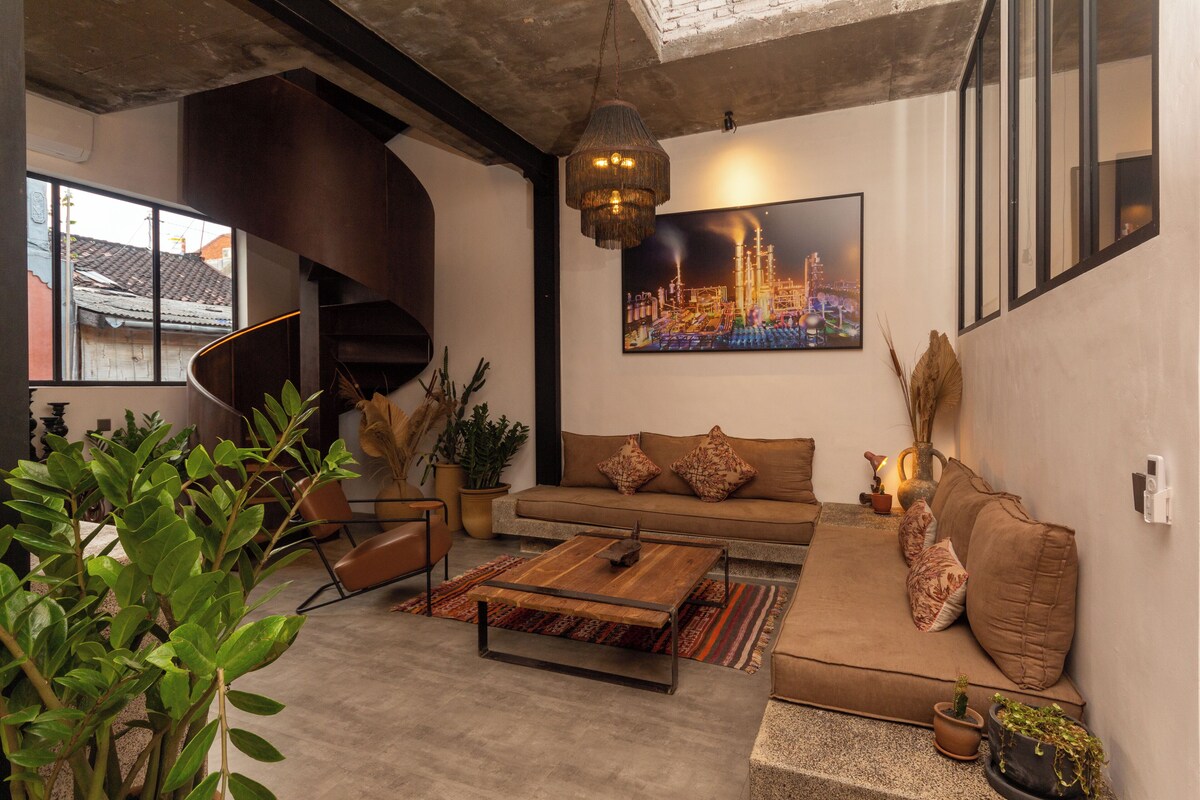 A modern living room with a sofa, coffee table, and potted plants.