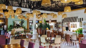 A spacious restaurant with high ceilings, wicker pendant lighting, and a variety of seating arrangements including tables and chairs. - Samkara Restaurant and Garden Resort (Lucban)