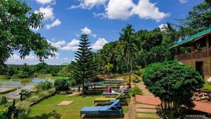 A tropical resort with a pool, lounge chairs, and a wooden building. - Samkara Restaurant and Garden Resort (Lucban)
