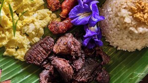 A variety of dishes including rice, sausages, scrambled eggs, and a bowl of soup, all served on a banana leaf. - Samkara Restaurant and Garden Resort (Lucban)