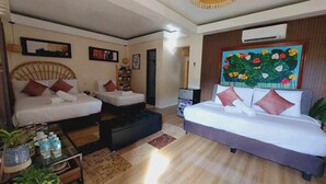 A hotel room with two single beds, a double bed, a small refrigerator, a TV, and a painting of flowers on the wall. - Samkara Restaurant and Garden Resort (Lucban)