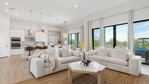 Ein großzügiges Wohnzimmer mit einer großen Couch, einem Couchtisch und einer Küchenzeile im Hintergrund.