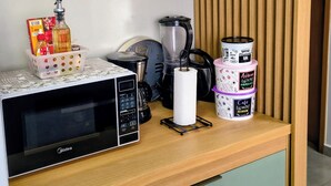 A kitchenette with a microwave, coffee maker, and storage containers.