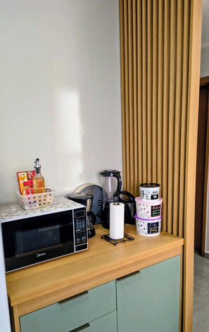 Uma cozinha compacta com micro-ondas, cafeteira e recipientes de armazenamento.