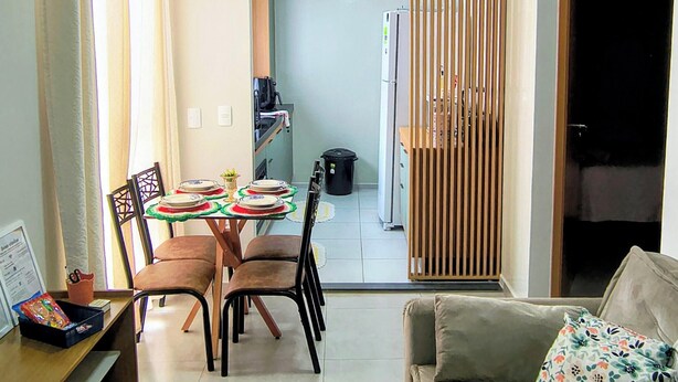 A living room with a sofa, a dining table with chairs, a kitchen area, and a sliding door leading to another room.