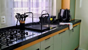 A kitchen with a gas stove, a coffee maker, and a sink.