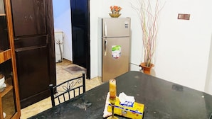 Eine kleine Küche mit Kühlschrank, Esstisch und einem Blumentopf.