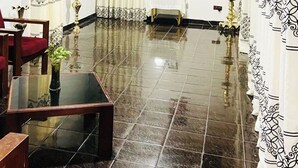 Eine Lobby mit glänzendem Fliesenboden, einem Glastisch und roten Sitzmöbeln.