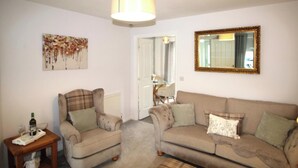 A living room with two armchairs, a sofa, a wooden side table, and a mirror on the wall. - House - Sleeps 4 - Pets Ok - Parking (Ashington)