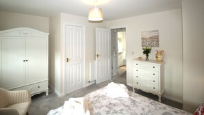 A bedroom with a bed, a chair, a dresser, and two doors. - House - Sleeps 4 - Pets Ok - Parking (Ashington)
