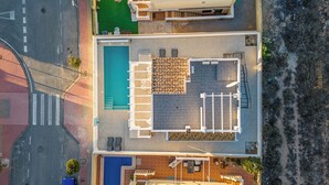 Vue aérienne d’un hôtel doté d’une piscine, d’un espace extérieur aménagé avec des si èges et d’une terrasse couverte.