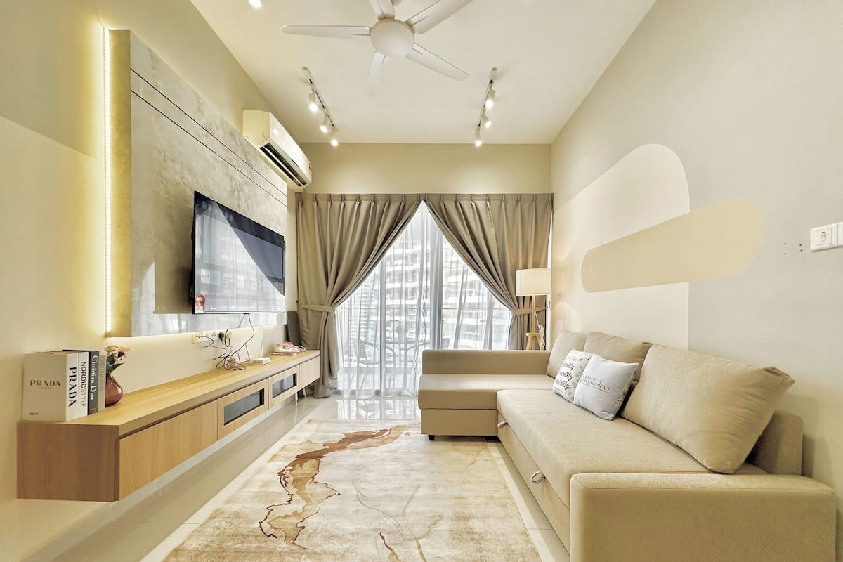 A modern living room with a sofa, TV, and a decorative rug.