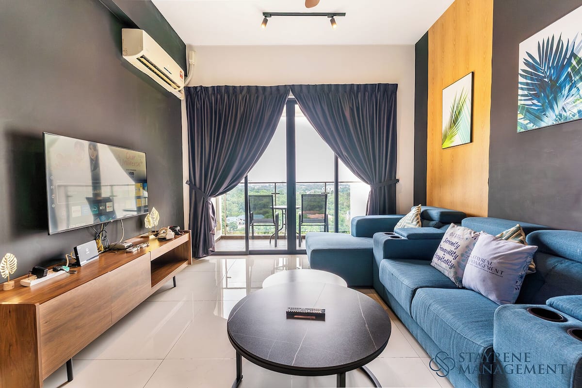 A modern living room with a flat-screen TV, a wooden console table, a blue sofa, and a round coffee table.