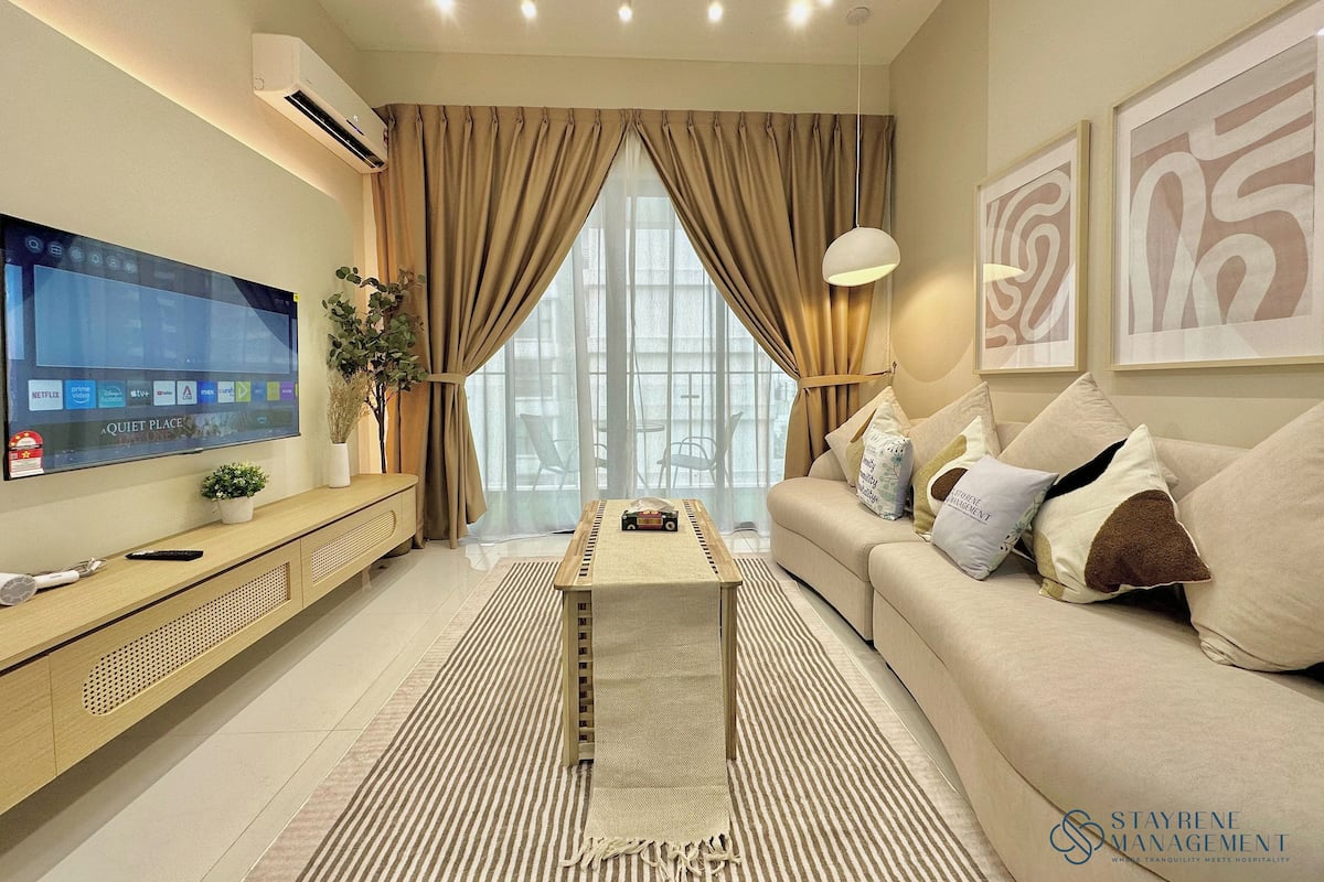 A modern living room with a flat-screen TV, a sofa, a coffee table, and a large window with curtains.