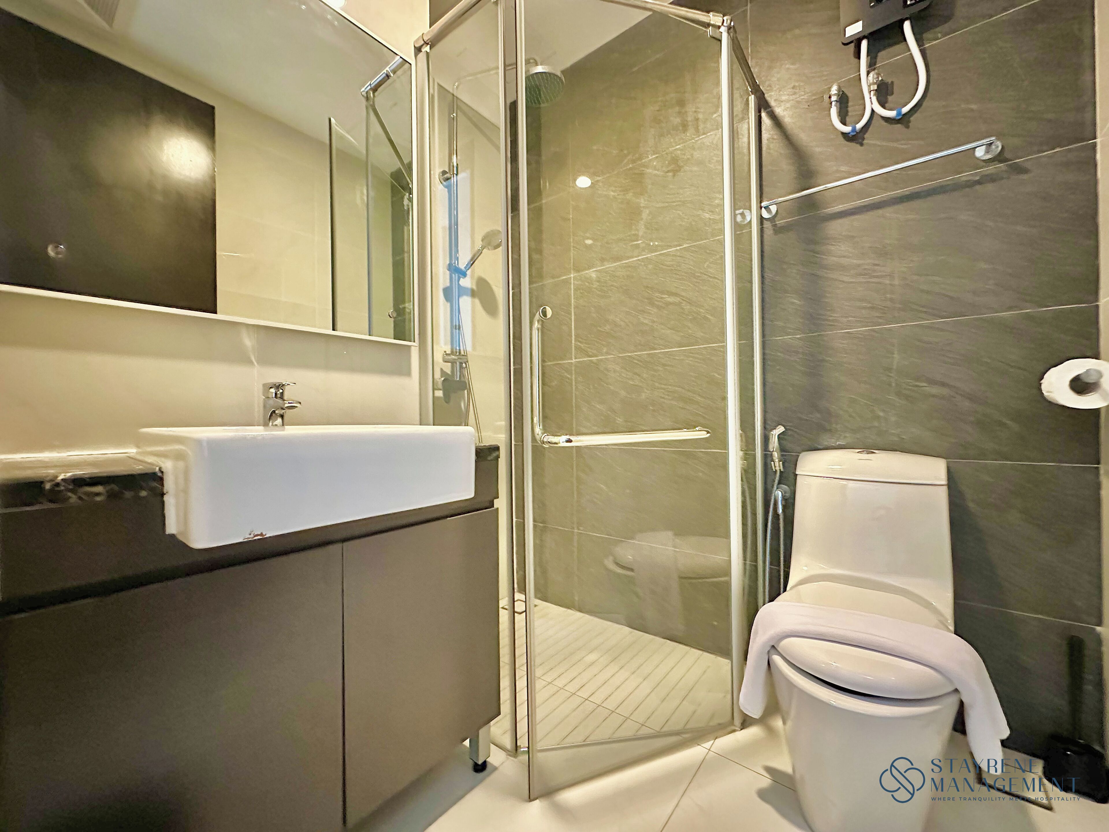 Een moderne badkamer met een douchecabine van glas, een wit wastafelmeubel en een toilet.