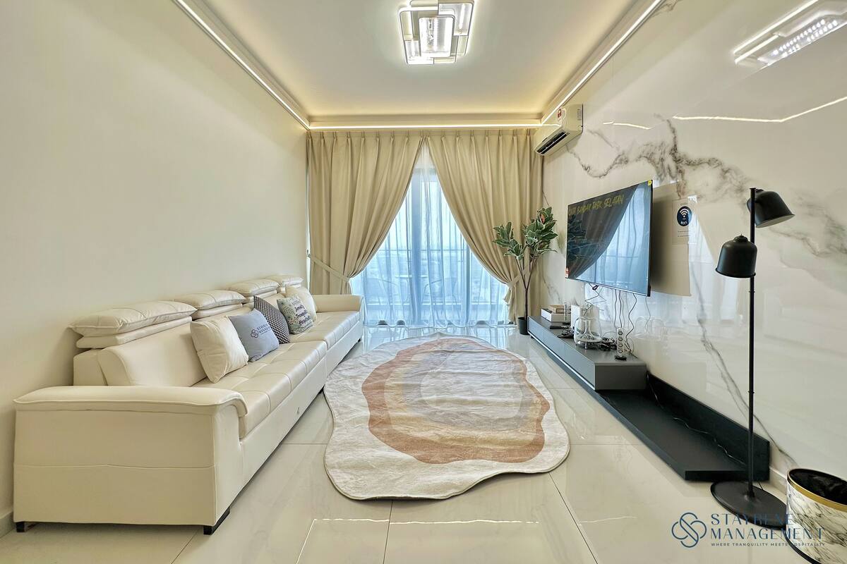 A modern living room with a sofa, a coffee table, a TV, and a large window with curtains.