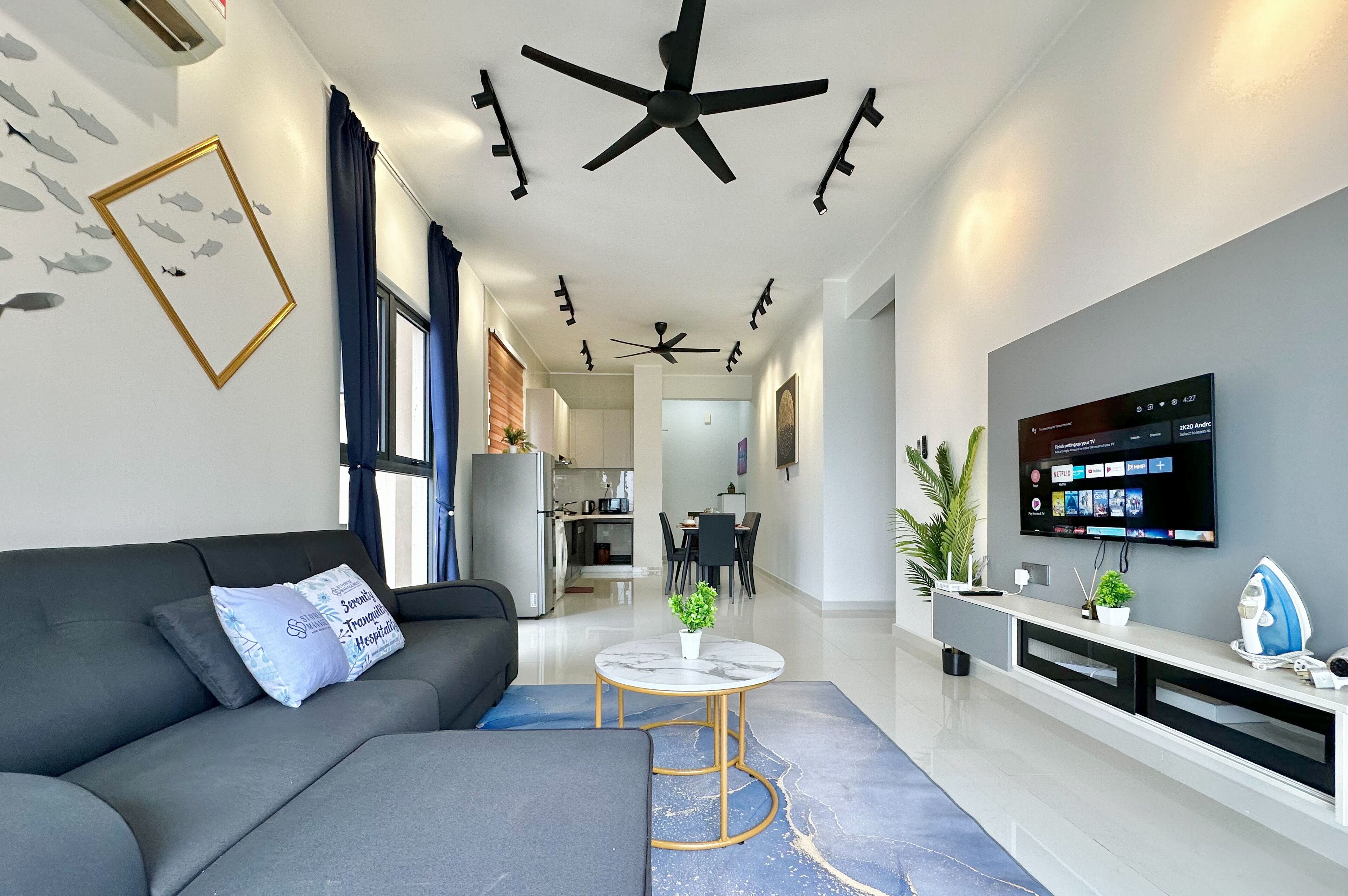 A modern living room with a grey sofa, a coffee table, and a TV mounted on the wall.