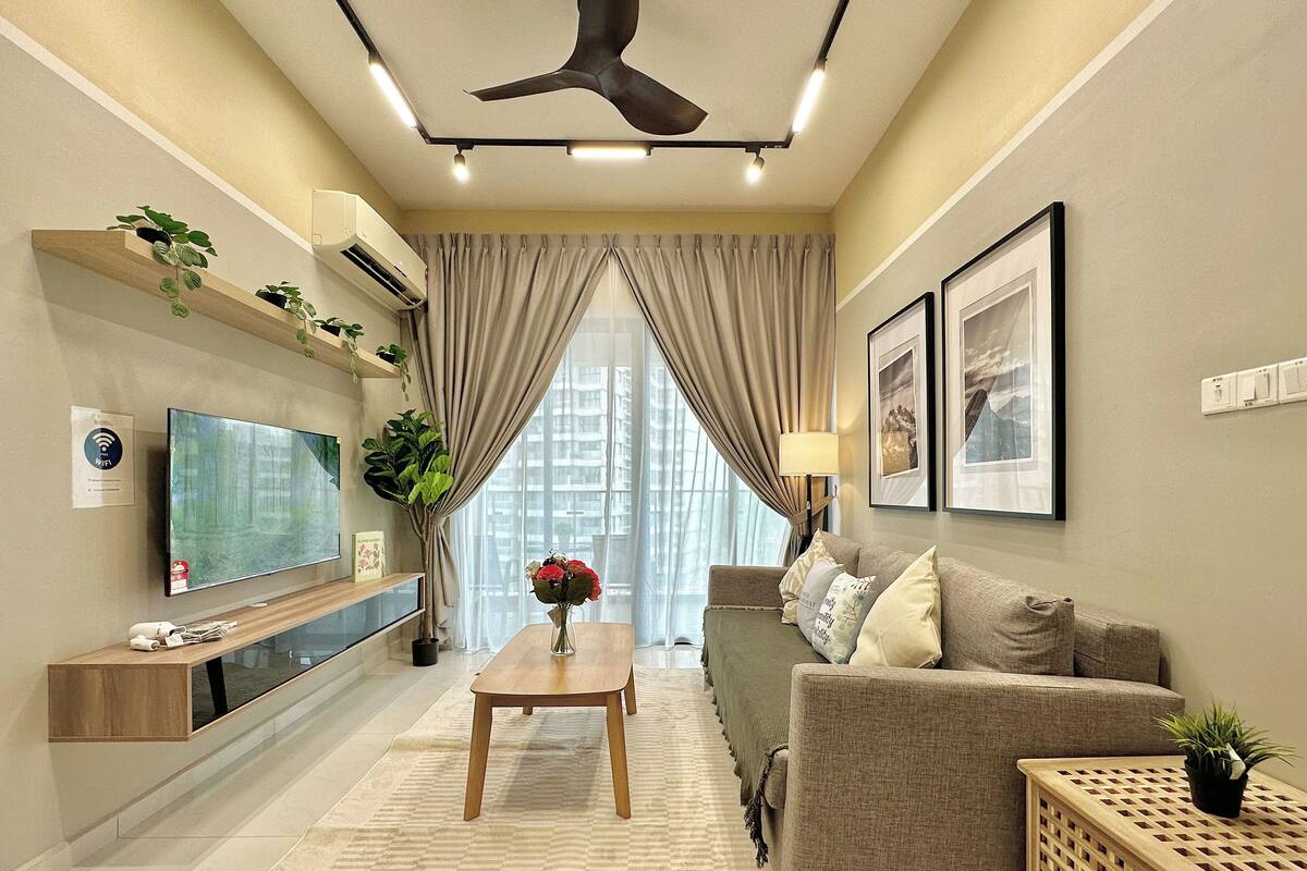 A modern living room with a flat-screen TV, a wooden coffee table, a sofa, and a decorative plant.