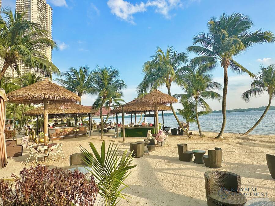 A beachside restaurant with thatched umbrellas, outdoor seating, and palm trees.