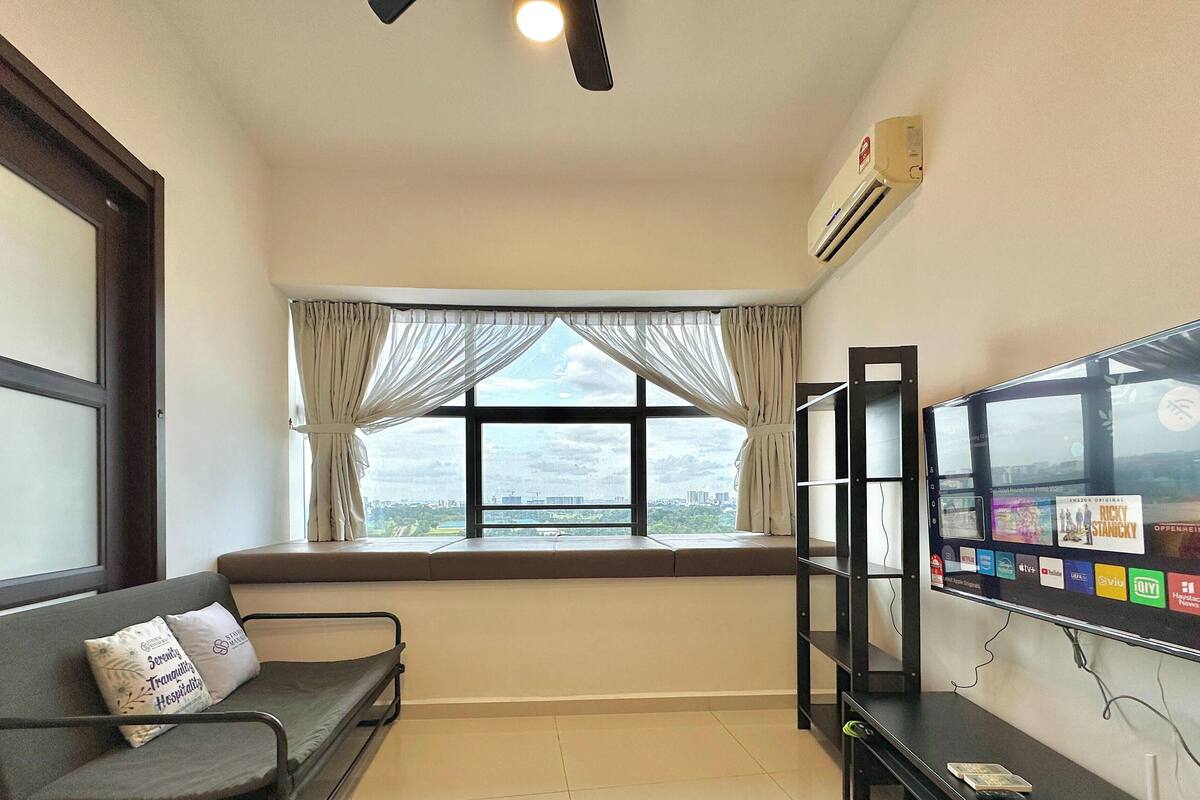 A room with a bed, a TV, and a window with curtains.