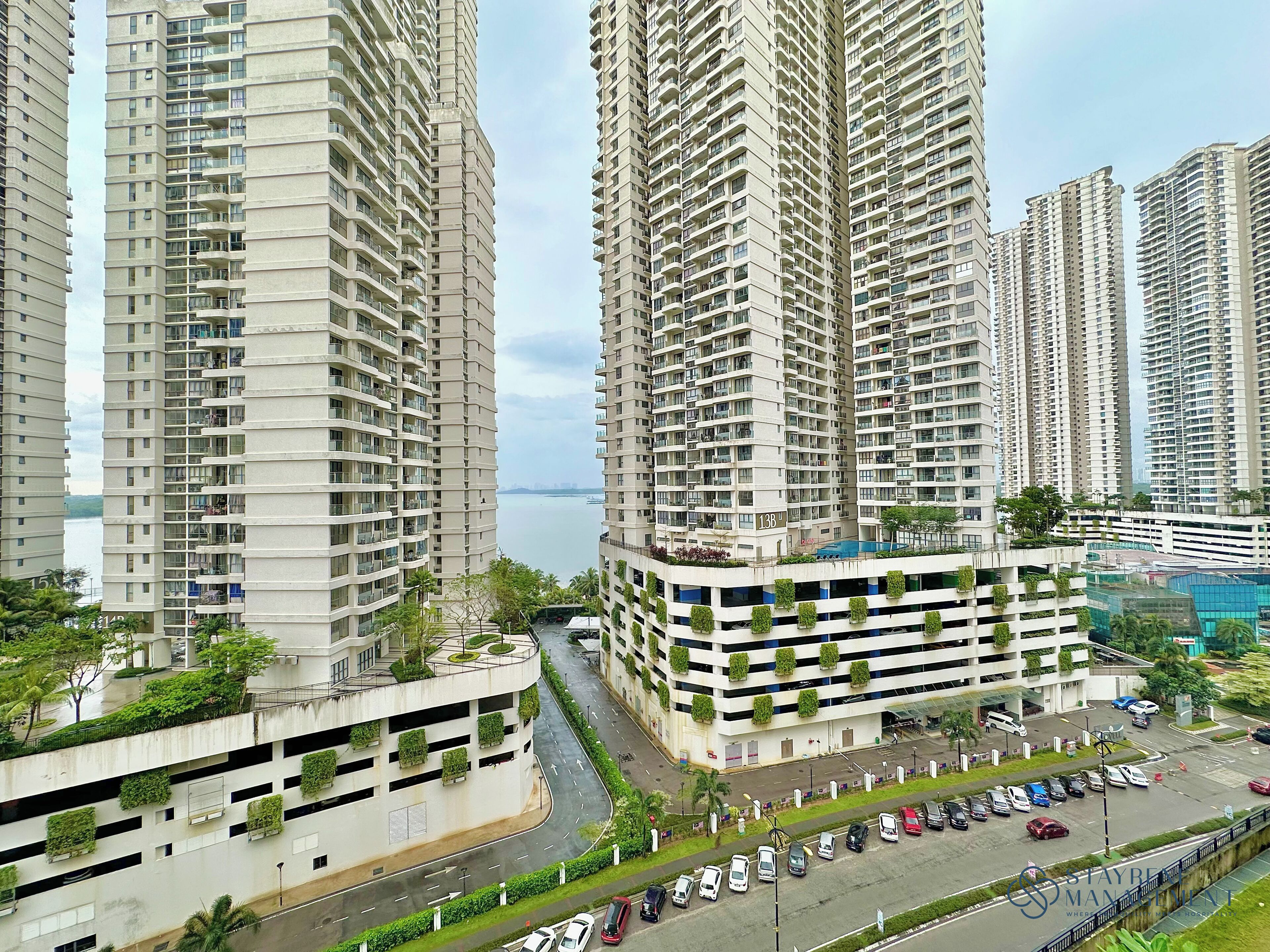 Un edificio residenziale a più piani con numerosi balconi, un'area parcheggio e vista sull'acqua.