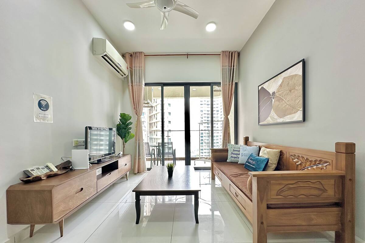 A modern living room with a wooden sofa, a coffee table, a TV, and a large window with curtains.