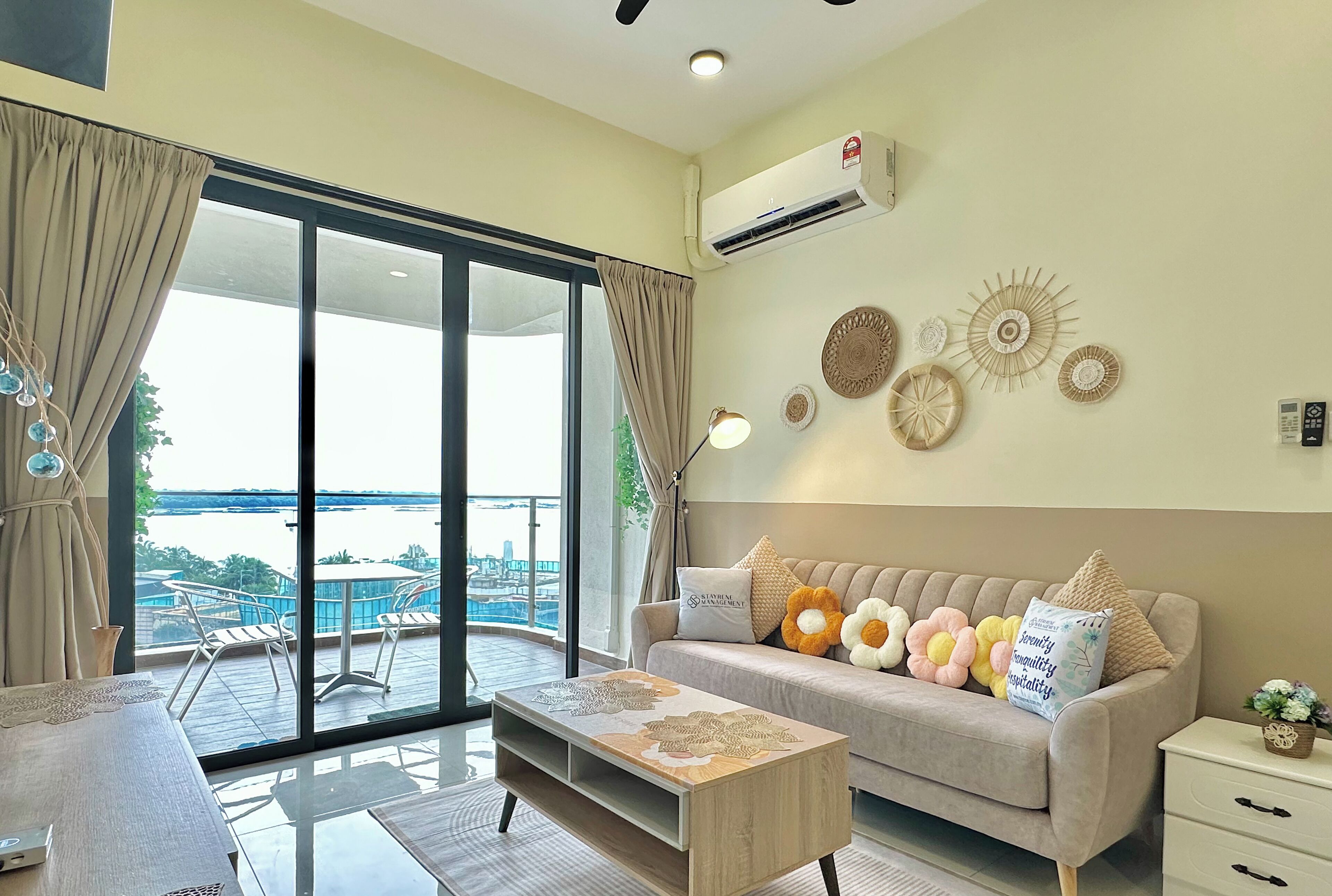 A modern living room with a sofa, coffee table, and a view of a pool and cityscape through large glass doors.