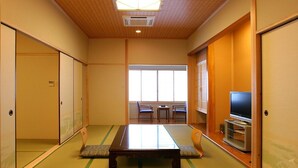 Habitació japonesa tradicional amb fons de tatami, una taula baixa, portes corredisses i un televisor.