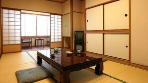 Una cambra japonesa tradicional amb fons de tatami, una taula de fusta baixa, televisió i portes corredisses.