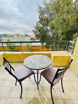 A round table with two chairs, a yellow wall, and a view of a building in the background. - Las Vegas Strip - Cozy 2-bedroom, 2 - bathroom condo with WiFi, AC, Pool & Gym (Las Vegas)